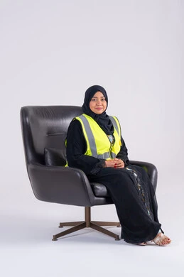 العمل في القطاع الهندسي، مفهوم الهندسة والانشاءات المعمارية، سيده اماراتيه تنظر بايماءات الفخر، تعابير السرور والسعادة والثقة بالنفس،بورتريه لمهندسة عربية خليجية سعودية محجبة ترتدي سترة الحماية