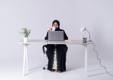 استخدم التقنيات الحديثة في الأعمال الإدارية ، امراه عربيه خليجيه سعوديه ترتدي العباءه والحجاب تجلس على مكتب وتعمل على جهاز الحاسب المحمول ، احتساء المشروبات الساخنه، سيده اماراتيه تقوم بالتركيز والتفاني والعمل الجاد، التوظيف في المكاتب والشركات ،دمج التكنولوجيا المتطوره فى الحياه اليوميه