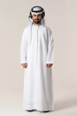 Spending enjoyable times using headphone technology, following music and entertainment with headphones, listening to musical clips, wearing audio headphones, a portrait of an Arab Gulf Emirati man wearing the Emirati kandura listening to songs with gestures of joy and happiness, white background.