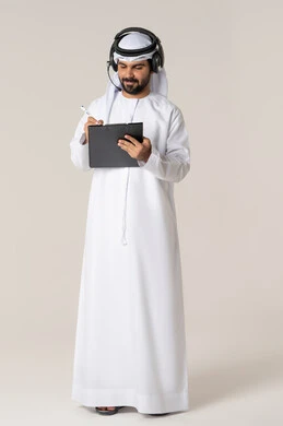 Recording ideas and information on paper pages, organizing and managing tasks, writing daily tasks and goals, a portrait of a smiling young Emirati Arab man wearing a kandura and a white ghutrah with headphones, holding a folder and a pen in his hand, full body, white background.