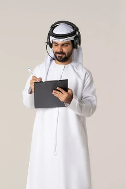 Taking handwritten notes to preserve details, organizing and managing tasks, writing daily tasks and goals, a portrait of a smiling young Emirati Arab man wearing a kandura and a white ghutrah with headphones, holding a folder and a pen, with a white background.
