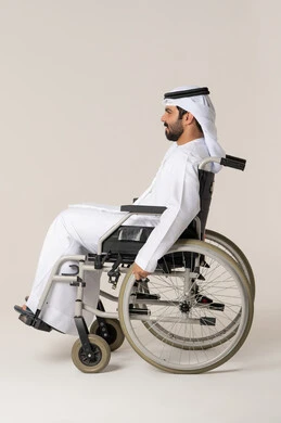 Providing devices and equipment that assist with movement and mobility, improving the lives of individuals with physical disabilities, a side portrait of an Emirati Gulf Arab man with special needs wearing a kandura and a white ghutrah sitting in a wheelchair, with a white background.