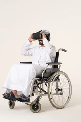 الاستمتاع بمحتوى مرئي غامر باستخدام الواقع الافتراض، بورترية لشاب عربي خليجي اماراتي من ذوى الاحتياجات الخاصة يرتدي الزي التقليدي و نظارات ثلاثية الأبعاد (الفي ار) يجلس على كرسي متحرك، التطور التقني والتكنولوجي, ، خلفية بيضاء