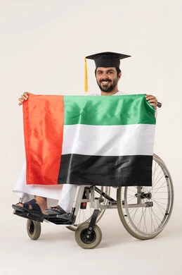 مشاعر الانتماء والارتباط بالبلاد، الأعياد والمناسبات الوطنية، بورترية لشاب عربي خليجي عماني من ذوى الاحتياجات الخاصة يرتدي الدشداشة و قبعه التخرج يجلس على كرسي متحرك و يمسك بيده علم عمان ، ايماءات السعادة و السرور ، خلفية بيضاء