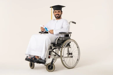 The joy of graduation and obtaining a university degree, the concept of diligence and excellence, a portrait of an Emirati Arab student with special needs wearing a white gown and graduation cap sitting in a wheelchair holding the certificate in his hand, the importance of university education and the joy of achieving success.