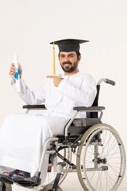 The feeling of joy, pride, and self-confidence, the concept of diligence and excellence, a portrait of an Emirati Arab student with special needs wearing a white gown and graduation cap sitting in a wheelchair holding the certificate and pointing to it, looking at the camera with gestures of satisfaction and happiness, the importance of university education and the joy of achieving success.