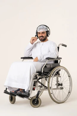 Listening to music using headphones, engaging and interacting with musical rhythms, artistic singing talents, a portrait of an Arab Gulf Emirati man with special needs wearing traditional attire sitting in a wheelchair listening to music through his headphones, looking at the camera with gestures of happiness and joy, white background.