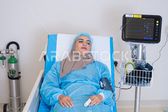 إجراءات علاجية دقيقة تتم في غرفة مجهزة بأحدث الأجهزة الطبية لضمان متابعة مستمرة لحالة المريضة,موعد مع الطبيب لتلقي العلاج, سيدة عربية خليجية اماراتية محجبة مستلقية على السرير في المستشفى