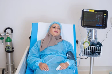 إجراءات علاجية دقيقة تتم في غرفة مجهزة بأحدث الأجهزة الطبية لضمان متابعة مستمرة لحالة المريضة,موعد مع الطبيب لتلقي العلاج, سيدة عربية خليجية اماراتية محجبة مستلقية على السرير في المستشفى