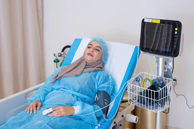 تقديم المساعدة الطبية للمرضى, جهاز مونيتور لمراقبة حالة السيدة الصحية, مريضة عربية خليجية اماراتية محجبة مستلقية على السرير في المستشفى