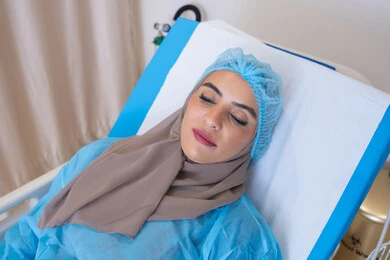 موعد مع الطبيب لتلقي العلاج, مريضة عربية خليجية اماراتية محجبة مستلقية على السرير في المستشفى, إجراء الفحوصات والمتابعة الدورية للمرضى