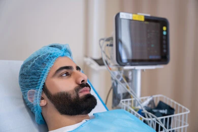 مريض عربي خليجي اماراتي في وضعية استرخاء أثناء مراقبة المؤشرات الحيوية, إيماءات الاندماج في التفكير, جهاز المونيتور لمراقبة نبضات القلب