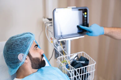 الإشارة بإصبع السبابة الي جهاز المونيتور, مريض عربي خليجي اماراتي مستلقي على سرير في المستشفى, مراقبة نبضات القلب, أجهزة ومعدات طبية في غرفة العمليات