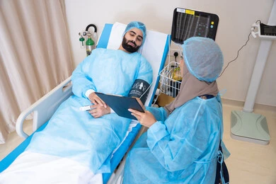 رعاية طبية متكاملة بوجود أحدث تقنيات المراقبة, أجواء يسودها الاطمئنان والدعم النفسي قبل العلاج, طبيبة عربية خليجية اماراتية محجبة تقوم بقياس الضغط للمريض, دمج التكنولوجيا الحديثة في المجال الطبي