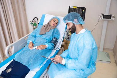 الطموحات والاهداف المستقبلية بالعمل في العيادات والمشافي، طبيب عربي خليجي اماراتي يرتدي المريول الطبي و يقوم بقراءة نتيجة الفحوصات عبر التابلت, مريضة محجبة مستلقية على سرير المشفى تنصت للطبيب الطموحات والاهداف المستقبلية بالعمل في العيادات والمشافي، طبيب عربي خليجي اماراتي يرتدي المريول الطبي و يقوم بقراءة نتيجة الفحوصات عبر التابلت, مريضة محجبة مستلقية على سرير المشفى تنصت للطبيب