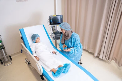 ولد يتلقى الرعاية الصحية في المستشفى,  تلقي العلاج والتشخيص الطبي في المستشفى, نظرات مليئة بالأمل والحب, طبيبة عربية خليجية اماراتية محجبة و ترتدي المريول الطبي