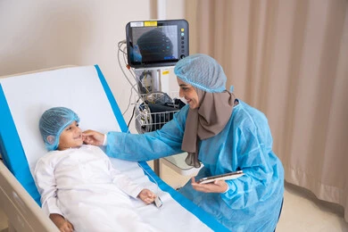 المواساة والتخفيف عن الولد المريض، تلقي العلاج والتشخيص الطبي في المستشفى, نظرات مليئة بالأمل والحب, طبيبة عربية خليجية اماراتية محجبة و ترتدي المريول الطبي