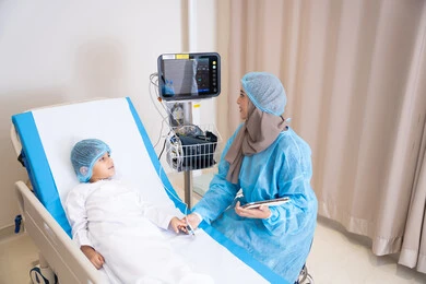 العناية بالمرضى داخل الوحدات الطبية, إيماءات اليد تدل على الاطمئنان والتهدئة، طبيبة عربية خليجية اماراتية محجبة ترتدي المريول الطبي و تمسك بيد ولد مريض