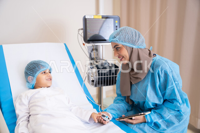 إيماءات اليد تدل على الاطمئنان والتهدئة، تقديم الاستشارات الطبية في المستشفيات، الرعاية الصحية والعلاج، طبيبة عربية خليجية اماراتية محجبة ترتدي المريول الطبي و تمسك بيد ولد مريض