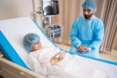 Providing services to patients efficiently, conducting medical consultations and therapeutic services, an Arab Gulf Emirati doctor wearing a medical apron and working in the hospital, measuring vital signs