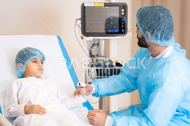 شاشة جهاز طبي تعرض معلومات وبيانات لعلاج المرضى, حجرة مجهزة بالأدوات الطبية الحديثة، استخدام التقنية والتكنولوجيا في العلاج، عيادات ومراكز صحية متطورة, طبيب عربي خليجي اماراتي يرتدي المريول الطبي و يعمل في المستشفى