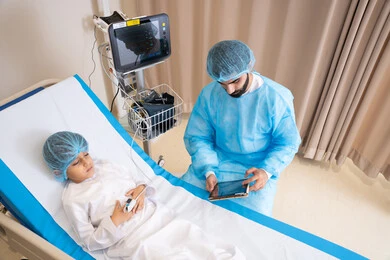 مفهوم الطب والرعاية الصحية, طبيب عربي خليجي اماراتي يقرأ فحوصات ولد مريض  يرتدي ملابس المستشفى عبر التابلت, استخدام التقنية والتكنولوجيا في العلاج