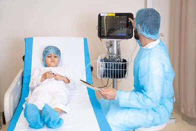 تقديم النصائح الطبية لولد مريض، قياس العلامات الحيوية, طبيب عربي خليجي اماراتي يرتدي المريول الطبي و  يعمل في المشفى, شاشة جهاز طبي تعرض معلومات وبيانات لعلاج المرضى