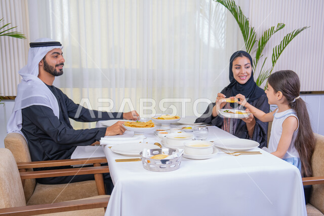التسلية والترفيه بالعطلات، صورة مقربة لعائلة عربية خليجية إماراتية يقومون بتناول الطعام تقدم الأم الطعام لطفلتها، قضاء وقت عائلي ممتع في مطعم فاخر، طاولة مليئة بأطباق الأطعمة الغربية، أجواء أسرية مليئة بالألفة والمحبة، الاهتمام بالغذاء وصحة الأطفال