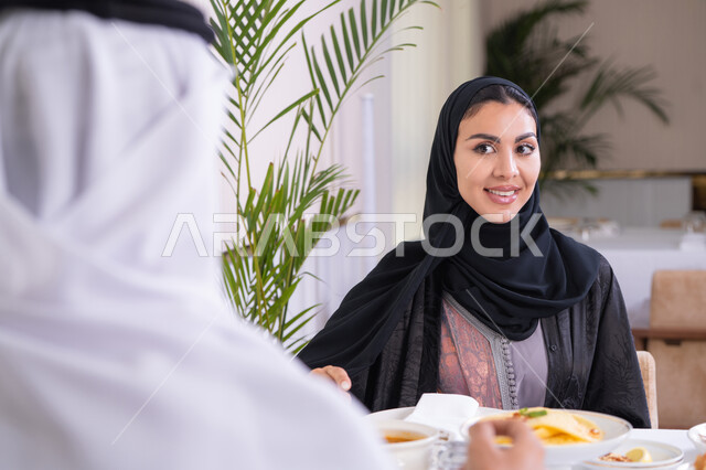 تقوية العلاقات الزوجية وروابط الحب والمودة، ، الخروج بسهرة مسائية عائلية، زوجان عربيان خليجيان اماراتيان يقضيان وقتهما سويا يجلسان على مائدة طعام في مطعم راقي، تشارك الأحاديث والمواضيع لتقريب وجهات النظر، صورة من الخلف لرجل عربي خليجي اماراتي