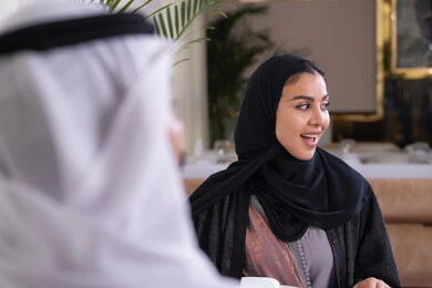 الاستجمام والترويح عن النفس بسهرة مسائية عائلية، تقوية العلاقات الزوجية وروابط الحب والمودة، زوجان عربيان خليجيان اماراتيان يقضيان وقتهما سويا يجلسان على مائدة طعام في مطعم راقي، تشارك الأحاديث والمواضيع