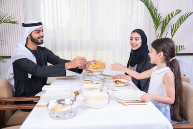 الذكريات واللحظات العائلية السعيدة، عائلة عربية خليجية إماراتية يقومون بتناول الطعام في مطعم راقي ، وضع الأطفال في بيئة عائلية مليئة بالألفة والمشاركة، طاولة مليئة بأطباق الأطعمة الغربية، الاستمتاع في عطلة نهاية الأسبوع، مفهوم الترابط الأسري