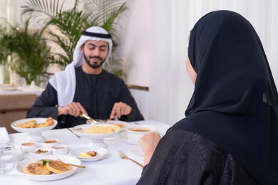 مائدة مليئة باطباق متنوعه ومختلفه من المأكولات الشهية، الألفة والمودة بين الزوجين، قضاء وقت ممتع خارج المنزل في عطلة نهاية الاسبوع, زوجان عربيان اماراتيان يقومان بتناول الطعام في المطعم, مفهوم الاسره السعيده