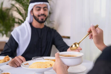 مائدة مليئة باطباق متنوعه ومختلفه من المأكولات الشهية، الألفة والمودة بين الزوجين، قضاء وقت ممتع خارج المنزل في عطلة نهاية الاسبوع, زوجان عربيان اماراتيان يقومان بتناول الطعام في المطعم, مفهوم الاسره السعيده