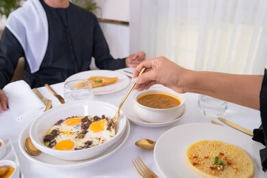 مشاركة الاطعمة بين الزوجين، مائدة مليئة باطباق متنوعه ومختلفه من المأكولات الشهية، الألفة والمودة بين الزوجين، قضاء وقت ممتع خارج المنزل في عطلة نهاية الاسبوع, زوجان عربيان اماراتيان يقومان بتناول الطعام في المطعم, مفهوم الاسره السعيده