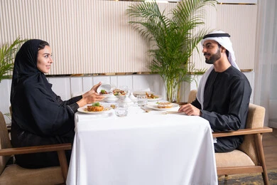 طاولة مليئة باطباق متنوعه ومختلفه من المأكولات الشهية، مفهوم المحبة والمودة بين الزوجين، قضاء وقت ممتعه خارج المنزل في عطلة نهاية الاسبوع, مطعم راقي في الامارات العربية المتحدة، زوجان عربيان اماراتيان يقوم بتناول الطعام في المطعم, مفهوم الاسره السعيده