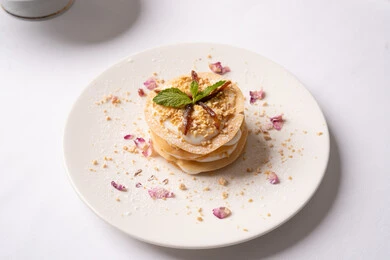 Delicious cold desserts, a delicious healthy breakfast, the art of presenting desserts in restaurants in the Kingdom of Saudi Arabia, a plate of delicious crepe layers decorated with cream, honey and nuts, foods rich in sugars and calories