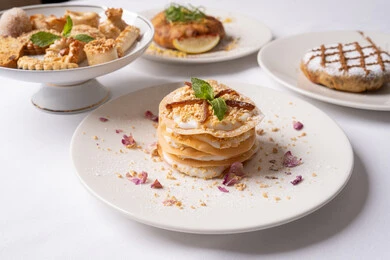Deliciously flavored baked sweets, a delicious and healthy breakfast, dishes and recipes made from fresh, crisp biscuits, the art of serving desserts in the Kingdom's restaurants, a plate of delicious crepe layers decorated with cream, honey, and nuts, foods rich in sugar and calories, and local national products and foods.