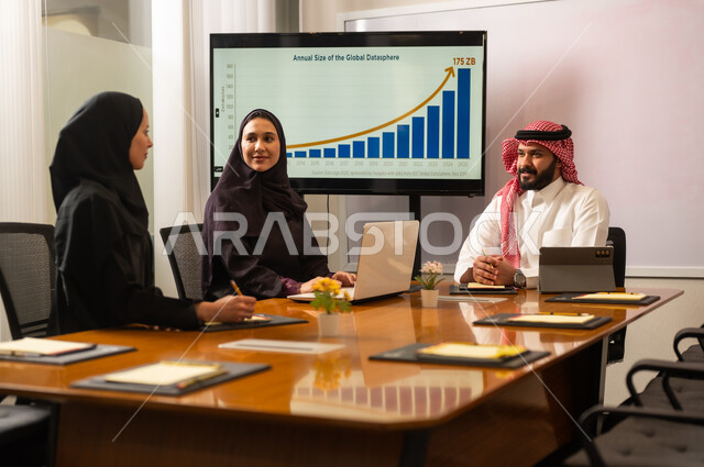 Using modern technical devices, unity and teamwork, studying and analyzing new projects, exchanging experiences and ideas, workshops and training, developing work and solving problems, holding a meeting for a team of Saudi Gulf Arab workers inside the company headquarters, a Saudi office profession and job.