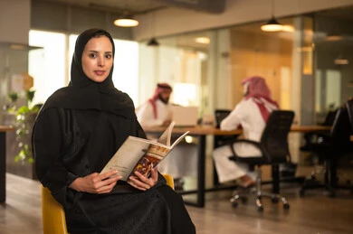 Looking at the camera with gestures of joy, enjoying reading magazines and books during a work break in a Saudi company, acceptance and approval between companies, studying and analyzing new projects, exchanging experiences and ideas, workshops and training, holding a meeting for a team of Arab Gulf Saudis inside the company headquarters.