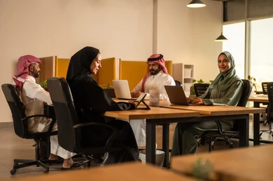 Project and investment development, studying statistical data papers, managing and dividing tasks, a Saudi Gulf Arab team conducting a business meeting in the company's conference room, explaining and analyzing graphs, integrating modern technical devices with office work.