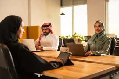 ابتسامةوتعابير الفرح، تطوير المشاريع و الاستثمارات، دراسة أوراق البيانات الإحصائية, إدارة و تقسيم المهام، فريق عمل عربي خليجي سعودي يقوم بإجراء اجتماع عمل داخل غرفة الاجتماعات في مقر الشركة،  دمج الأجهزة التقنية الحديثة بالأعمال المكتبية