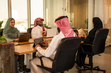 مناقشة ومتابعة الاعمال وتحقيق الاهداف المطلوبة, ارتداء اللباس السعودي التقليدي, تطوير المشاريع و الاستثمارات، دراسة أوراق البيانات الإحصائية, إدارة و تقسيم المهام، فريق عمل عربي خليجي سعودي يقوم بإجراء اجتماع عمل داخل غرفة الاجتماعات في مقر الشركة