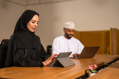 انجاز الاعمال على جهاز التابلت،  التركيز والعمل المتقن, الحوارات والنقاشات ضمن الفريق,تطوير الاعمال والشركات, اجتماع عمل وانجاز المشاريع, مناقشة الخطط وشرح مهام الاعمال, زملاء عمل عرب عمانيين خليجيين في اجتماع, ارتداء اللباس العماني التقليدي