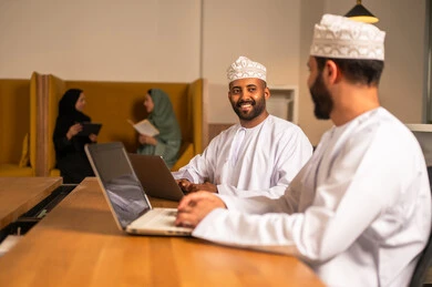 Love and happy times among colleagues, focus and meticulous work, dialogues and discussions within the team, business and company development, work meetings and project completion, discussing plans and explaining work tasks, Arab Omani Gulf colleagues in a meeting, wearing traditional Omani attire.