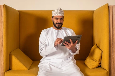 Online work meeting and project completion, working in Omani offices and companies, focus and meticulous work, dialogues and discussions within the team, business and company development, discussing plans and explaining work tasks, an Arab Gulf Omani employee within an Omani company, wearing traditional Omani attire.