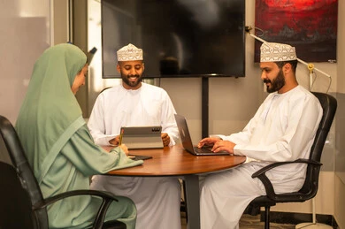 Focus and meticulous work, dialogues and discussions within the team, business and company development, work meetings and project completion, discussing plans and explaining work tasks, colleagues from Oman and Gulf Arab countries in a meeting, wearing traditional Omani attire.