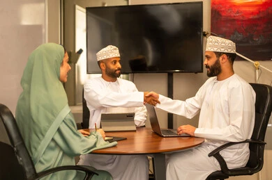 Focus and meticulous work, dialogues and discussions within the team, business and company development, work meetings and project completion, discussing plans and explaining work tasks, colleagues from Oman and Gulf Arab countries in a meeting, wearing traditional Omani attire.