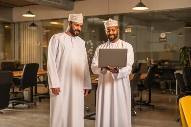 صفقات عمل جديدة ناجحة بين رجال الأعمال،الاتفاق والشراكة على الأعمال والمشاريع التجارية، تعارف وصداقات وبناء علاقات اجتماعية،  رجلان عربيان خليجيان عمانيان يقومان بشرح خطة العمل داخل ممقر الشركة بإيماءات السعادة والسرور