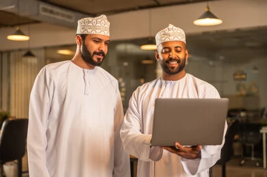 Successful new business deals between businessmen, agreements and partnerships on business and commercial projects, acquaintance and friendships, and building social relationships. Two Arab Gulf men from Oman are explaining the business plan inside the company's headquarters with gestures of happiness and joy.