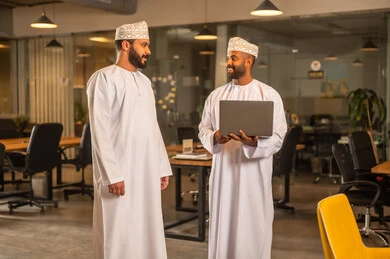 Writing and noting something, hanging colorful sticky notes, the work environment in Omani companies, office professions and jobs, a close-up image of an Omani Gulf Arab woman sticking a note on a glass surface inside the office.